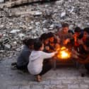 Children warm up by the fire at the Bureij camp for displaced Palestinians on December 30, 2024, amid the continuing war between Israel and the militant Hamas group. Since the war between Israel and Hamas began in October last year, Gaza's 2.4 million residents have endured severe shortages of electricity, drinkable water, food and medical services. (Photo by Eyad BABA / AFP) (Photo by EYAD BABA/AFP via Getty Images)