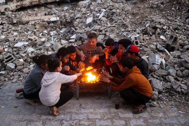 Children warm up by the fire at the Bureij camp for displaced Palestinians on December 30, 2024, amid the continuing war between Israel and the militant Hamas group. Since the war between Israel and Hamas began in October last year, Gaza's 2.4 million residents have endured severe shortages of electricity, drinkable water, food and medical services. (Photo by Eyad BABA / AFP) (Photo by EYAD BABA/AFP via Getty Images)