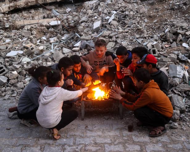 Children warm up by the fire at the Bureij camp for displaced Palestinians on December 30, 2024, amid the continuing war between Israel and the militant Hamas group. Since the war between Israel and Hamas began in October last year, Gaza's 2.4 million residents have endured severe shortages of electricity, drinkable water, food and medical services. (Photo by Eyad BABA / AFP) (Photo by EYAD BABA/AFP via Getty Images)
