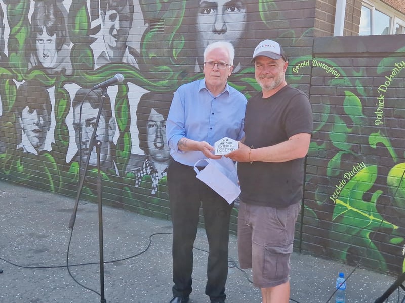 John Kelly presenting artist Jonny McKerr with a model of Free Derry Corner.