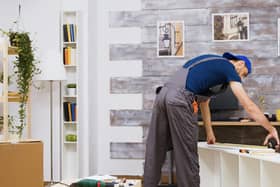 A man measures wood panels during a DIY home renovation project.