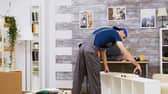 A man measures wood panels during a DIY home renovation project.