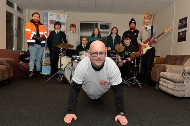 Brendan Donnelly, a volunteer with Reach Across cross-community youth group , pictured completing the last of his 30 days of push-ups, on Wednesday evening last, raising £420 for Foyle Search and Rescue. Included in the photograph are Rossa Smallman, FSR and members of the Reach Across band. Photo: George Sweeney. DER2248GS – 43