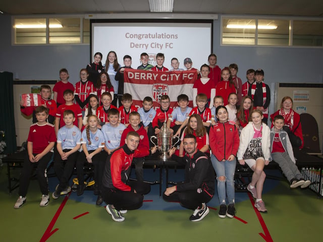 Derry players Caoimhin Porter and Michael Duffy and the FAI Cup pictured with the P7 classes at Greenhaw PS.