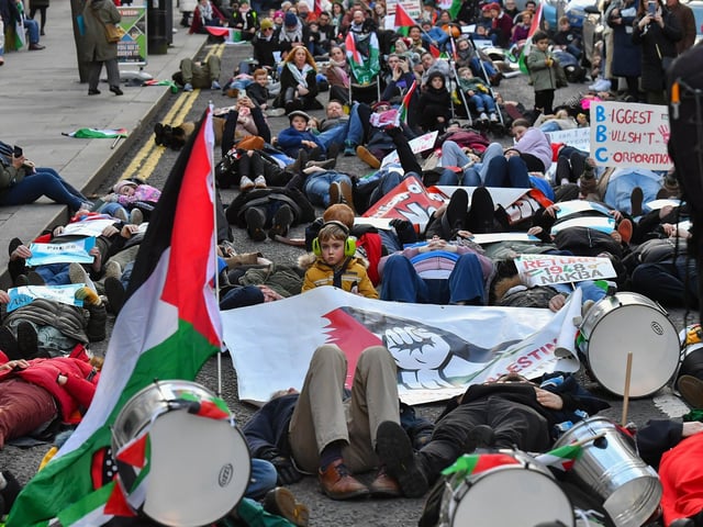 People taking part in a pro-Palestinian solidarity march “lay dead” on Shipquay Street, on Saturday afternoon to highlight the number of Palestinians who have been killed by Israel. Photo: George Sweeney