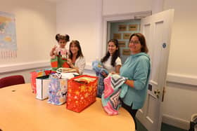 Siobhan McNally of the Derry Square Knitters presenting bags of handcrafted items to North West Migrants Forum staff members Aynaz Zarifmahmoudi and Evangelia Kasmeti with a little help from toddler Halumi.