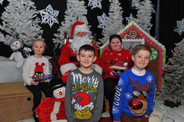 St Eithne’s Primary School P4 pupils Lauran, Olly, Liam and Leah from Mrs Coyle’s class pictured with Santa during his visit on Friday. Photo: George Sweeney. DER2250GS – 51
