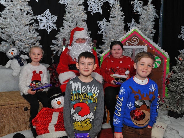 St Eithne’s Primary School P4 pupils Lauran, Olly, Liam and Leah from Mrs Coyle’s class pictured with Santa during his visit on Friday. Photo: George Sweeney. DER2250GS – 51