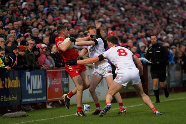 Derry's Ciaran McFaul tussles with Brian Kennedy and Seanie O'Donnell in Celtic Park on Sunday. Photo: George Sweeney