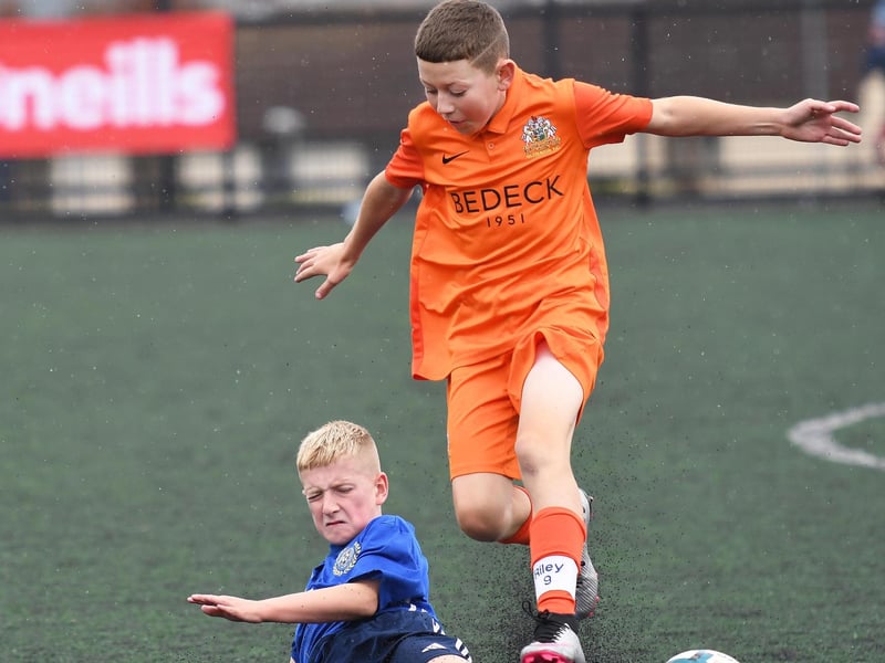 Glenavon FC forward Riley Topping hurdles this tackle from Shankill Juniors defender Kylan Morrison during their O'Neills Foyle Cup Under-11's final.
