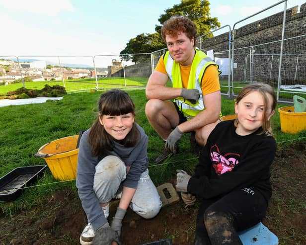 Gaelscoil Eadain Mhoir pupils Kaia Boyle and Bree Whoriskey pictured with archaeologist Conall O’Neill at the Queen’s University Centre for Community Archaeology dig in an area beneath the City Walls. Photo: George Sweeney
