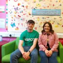 YPBC member Markus Smith with NSPCC Senior Participation Officer, Sinead McSorley at the Childline Foyle base. Each flower on the wallboard represents a young person who has contacted Childline