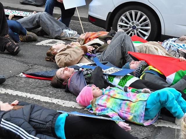 People taking part in a pro-Palestinian solidarity march “lay dead” on Shipquay Street, on Saturday afternoon to highlight the number of Palestinians who have been killed by Israel. Photo: George Sweeney