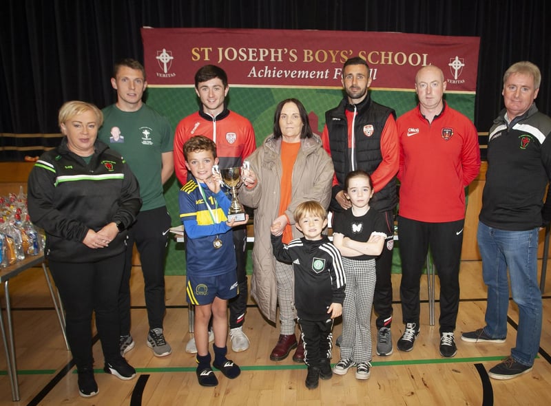 Don Bosco’s FC, winners of the 2013 Sean O’Kane Memorial Cup are presented with the trophy by Mrs. Breige O’Kane and her grandchildren on Sunday afternoon. Included from left are, Annette McCallion, Emmett McGinty, organiser/teacher, Declan Glass and Daniel Lafferty, Derry City, Chris McGeehan, organiser and Paul Kealey, Vice Principal, St. Joseph’s Boys School.