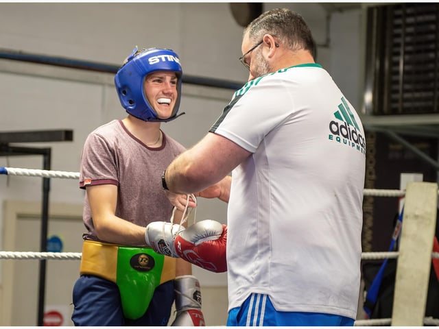Kevin Duffy shares a joke with this young boxer as he prepares his gloves ahead of a sparring session.
