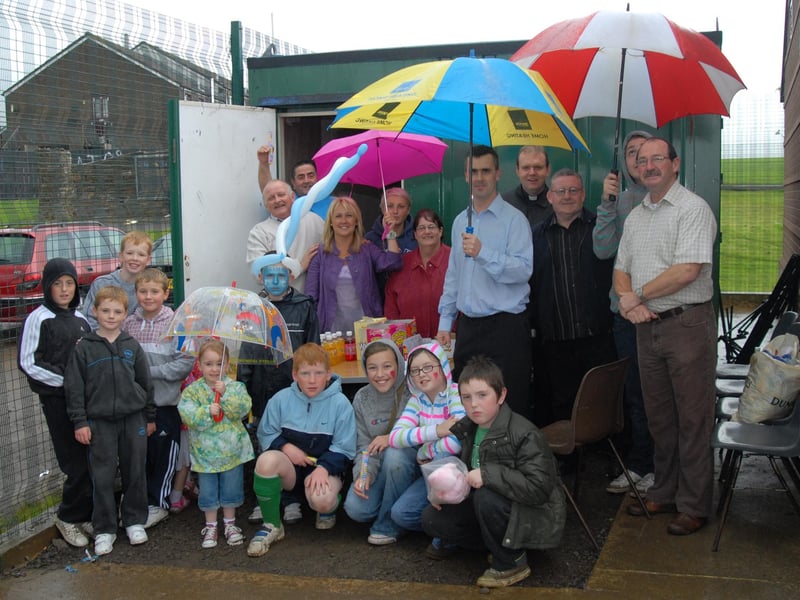 Father Gormley, Martin Connolly, Ciara Ferguson, Tony Hassan, Rory McPartland, Peter McDonald, Peter Griffin and Marie George pictured with local children who braved the rain at the Leafair Pitches on Friday afternoon. 1508Ap7
