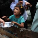 A Palestinian girl holds an empty pan at a hot meal distribution point in Nuseirat in the central Gaza Strip. Picture: Eyad Baba/AFP via Getty Images