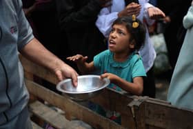 A Palestinian girl holds an empty pan at a hot meal distribution point in Nuseirat in the central Gaza Strip. Picture: Eyad Baba/AFP via Getty Images