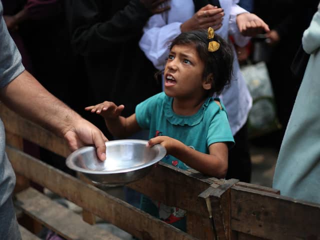 A Palestinian girl holds an empty pan at a hot meal distribution point in Nuseirat in the central Gaza Strip. Picture: Eyad Baba/AFP via Getty Images