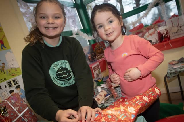 P7 pupil Jaida Holden gets some help Christmas wrapping from 3 years-old Isla Harkin at Oakgrove PS on Thursday. : .