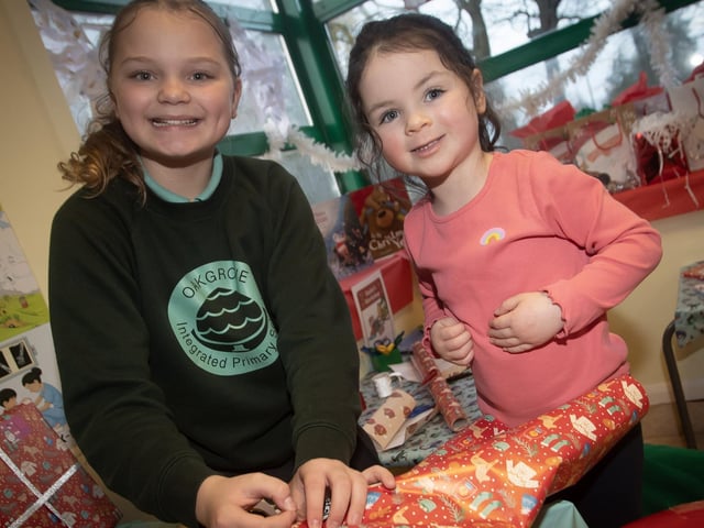 P7 pupil Jaida Holden gets some help Christmas wrapping from 3 years-old Isla Harkin at Oakgrove PS on Thursday. : .