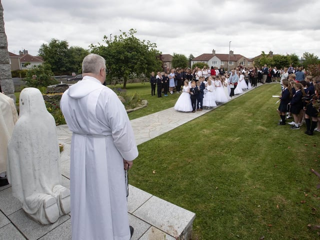 The children make their way to the Grotto at St. Mary's Church on Thursday as the school choir perform alongside.