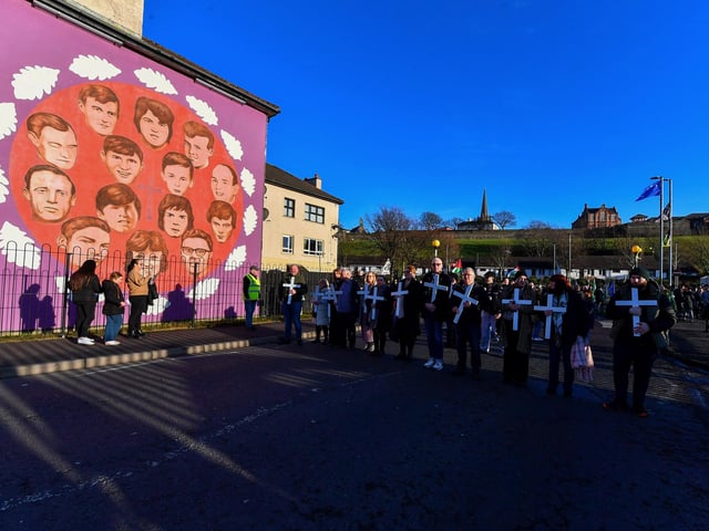 Relatives carrying white crosses stop for a moment of remembrance at a mural dedicated to those murdered on Bloody Sunday, during Sunday’s March for Justice. Photo: George Sweeney
