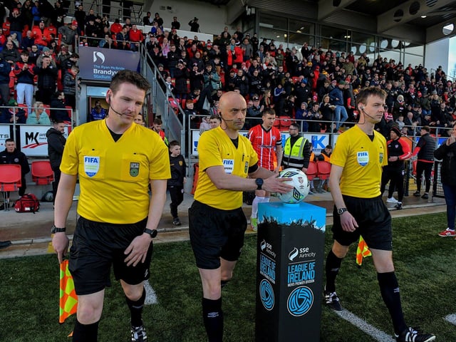 Match referee Neil Doyle leads the teams onto the pitch at the Brandywell on Monday evening. Photo: George Sweeney. DER2315GS – 119