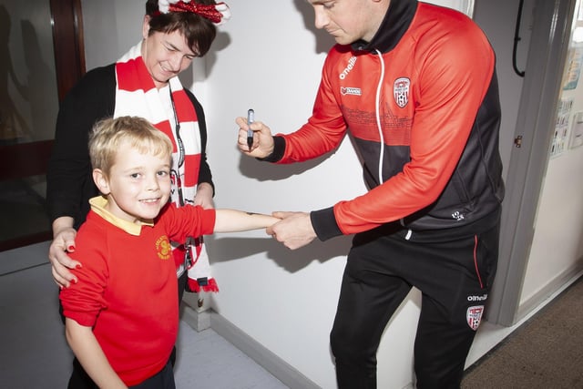 Pupil Jude getting the special signatureof Shane. McEleney during Tuesday’s visit to the school. Included is Classroom Assistant Mrs O'Doherty.