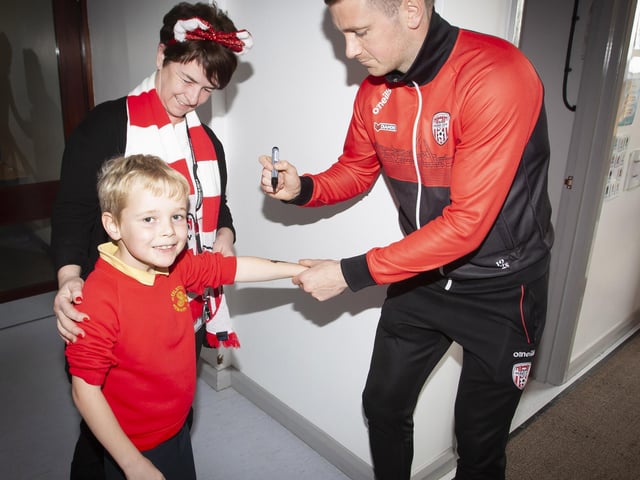 Pupil Jude getting the special signatureof Shane. McEleney during Tuesday’s visit to the school. Included is Classroom Assistant Mrs O'Doherty.