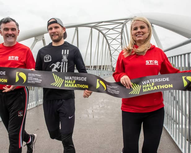 Waterside Half Marathon reigning senior men’s champion Kyle Doherty from City of Derry Spartans promoting the event on the Pennyburn Footbridge with Star Running Club members Patrick McCarry and Louise Wilkinson.