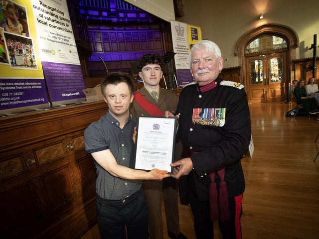 The Vice Lord Lieutenant Alan Moore, OBE, presenting the King's Award for Voluntary Service certificate to Benjamin Thompson on behalf of the Foyle Down Syndrome Trust, in the Guildhall on Friday last. At back is Sgt. Niall Downey, Irish Guards. (Photos: Jim McCafferty Photography)
