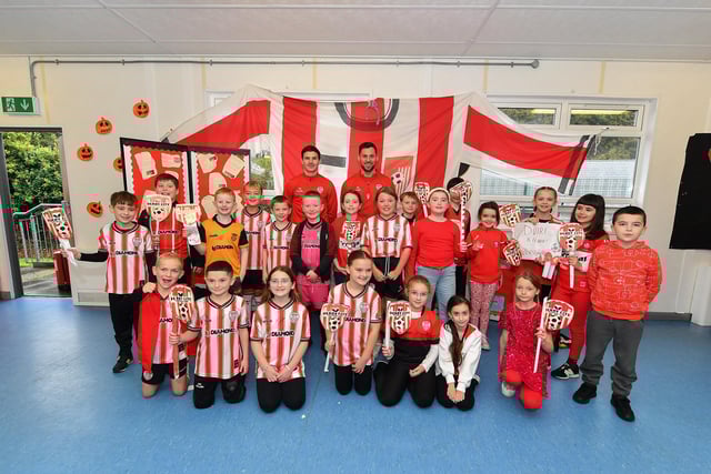 Pupils from Gaelscoil Eadain Mhoir pictured with Derry City’s Ciaran Coll and Pat Hoban during their visit to the school on Monday morning. Photo: George Sweeney
