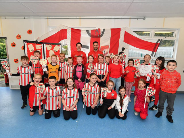 Pupils from Gaelscoil Eadain Mhoir pictured with Derry City’s Ciaran Coll and Pat Hoban during their visit to the school on Monday morning. Photo: George Sweeney