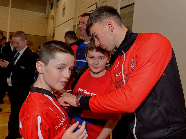 Derry Citys Liam Mullan signs autographs for pupils during a visit to the school, with the FAI Cup, on Monday . Photo: George Sweeney. DER2247GS 29