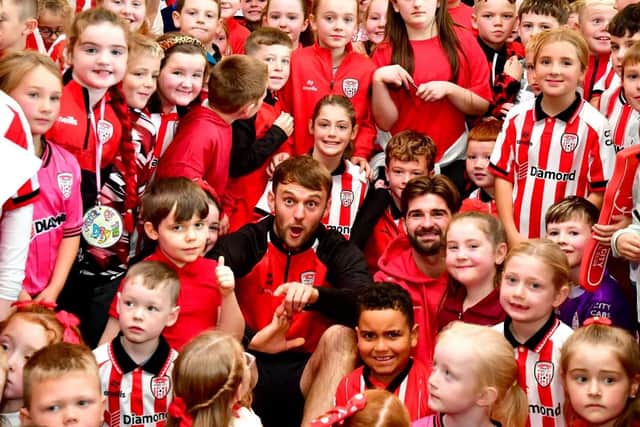 Derry City's Jamie Stott and Brandon Fleming amongst some of the pupils of St Therese PS who attended the school's red and white day in preparation for the FAI Cup Final.