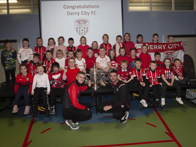 Derry players Caoimhin Porter and Michael Duffy and the FAI Cup pictured with the P3 classes at Greenhaw PS.