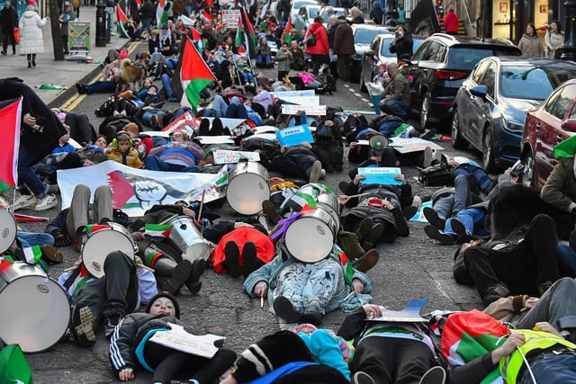 People taking part in a pro-Palestinian solidarity march “lay dead” on Shipquay Street, on Saturday afternoon  to highlight the number of Palestinians who have been killed by Israel.  Photo: George Sweeney