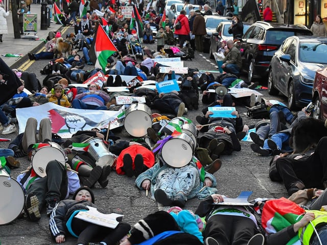 People taking part in a pro-Palestinian solidarity march “lay dead” on Shipquay Street, on Saturday afternoon to highlight the number of Palestinians who have been killed by Israel. Photo: George Sweeney