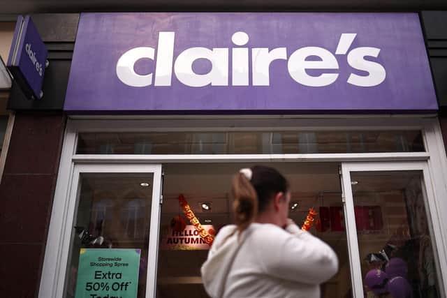Members of the public walk past a branch of "Claire's". (Photo by HENRY NICHOLLS/AFP via Getty Images)