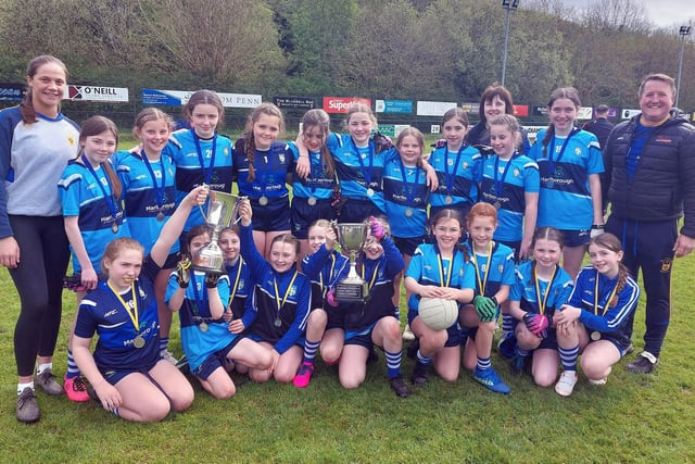 Hollybush PS girls' squad who recently qualified for the Cumann na mBunscol City Finals. Included in the picture are Dara Mc Keever (who just finished her teaching practice at Hollybush), Gary Cunningham, School GPO, and the Ladies Ulster Championship trophy.