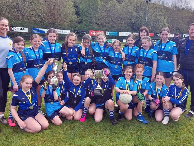 Hollybush PS girls' squad who recently qualified for the Cumann na mBunscol City Finals. Included in the picture are Dara Mc Keever (who just finished her teaching practice at Hollybush), Gary Cunningham, School GPO, and the Ladies Ulster Championship trophy.