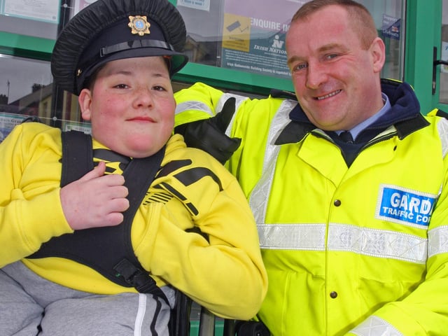 MAKE MY DAY!. . . Garda Traffic Corp officer Colm Mooney lets young Jim O'Brien try out the hat, at the St. Patrick's Day Parade in Buncrana. 1903JM65