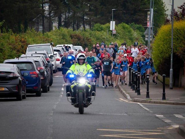 HOME STRETCH!. . . .This batch of runners are led home by a motorcycle outrider during Friday’s Run Challenge.