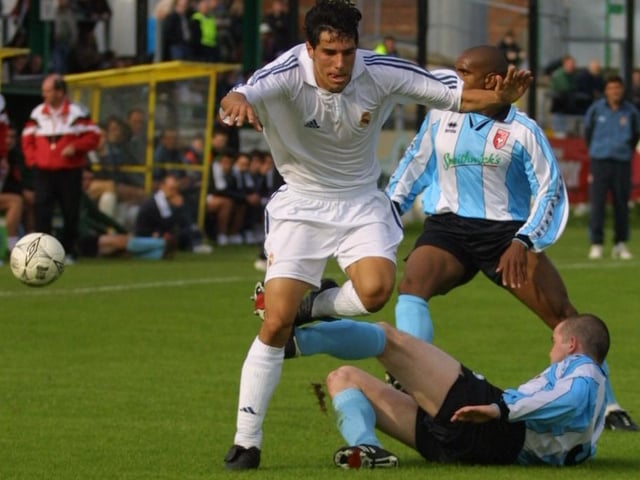 Sean Hargan gets in a challenge on Real forward while Derek Phillips awaits the outcome.(2208JB79)