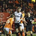 Morecambe's Jacob Davenport heads the ball clear under pressure from Blackpool's Luke Mariette.