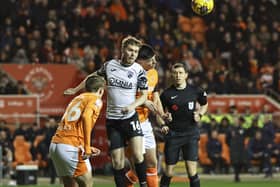 Morecambe's Jacob Davenport heads the ball clear under pressure from Blackpool's Luke Mariette.