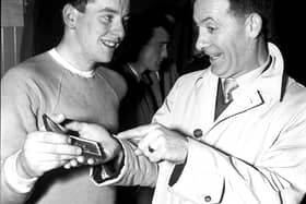 ‘I know how you feel', says Charlie Heffron - Derry City's goalkeeper when the ‘Candy Stripes' won the cup in 1954 - to city's young netminder, Eddie Mahon, as Eddie shows Charlie his cup winners' medal in the dressing room of Windsor Park.