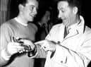 ‘I know how you feel', says Charlie Heffron - Derry City's goalkeeper when the ‘Candy Stripes' won the cup in 1954 - to city's young netminder, Eddie Mahon, as Eddie shows Charlie his cup winners' medal in the dressing room of Windsor Park.