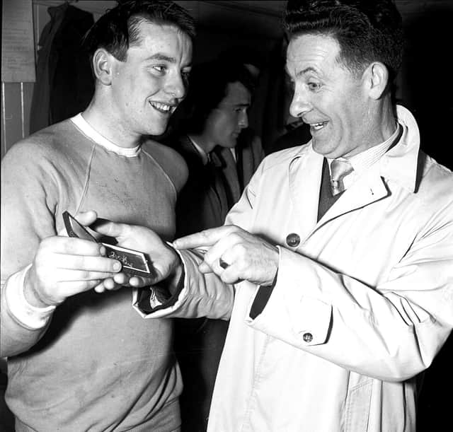 ‘I know how you feel', says Charlie Heffron - Derry City's goalkeeper when the ‘Candy Stripes' won the cup in 1954 - to city's young netminder, Eddie Mahon, as Eddie shows Charlie his cup winners' medal in the dressing room of Windsor Park.